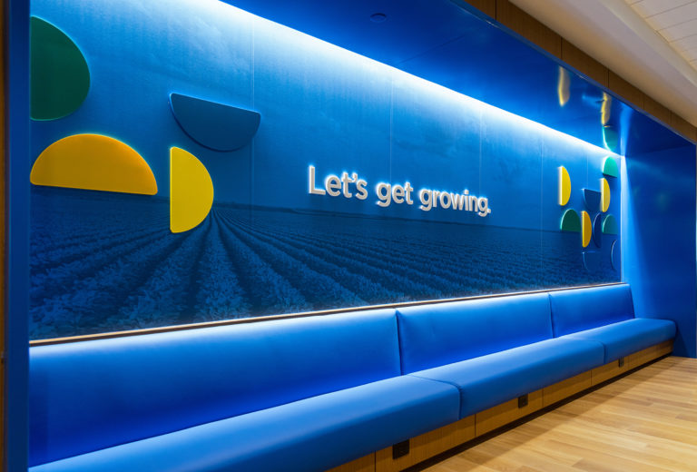 Wall installation outside the board room features a blue image of a field and the words, "let's get growing" framed by segments from the Scoular logo.