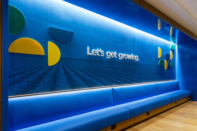 Wall installation outside the board room features a blue image of a field and the words, "let's get growing" framed by segments from the Scoular logo.