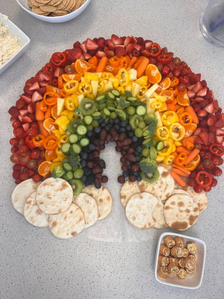 An elaborate tabletop spread of food in the shape of a rainbow