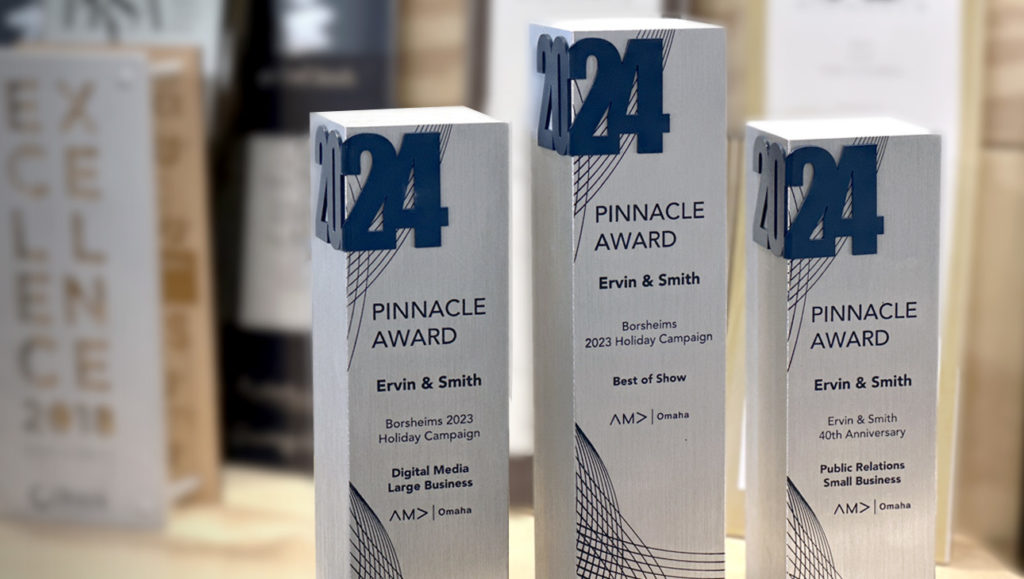 Three Pinnacle awards, awarded to Ervin & Smith displayed on plywood shelf.