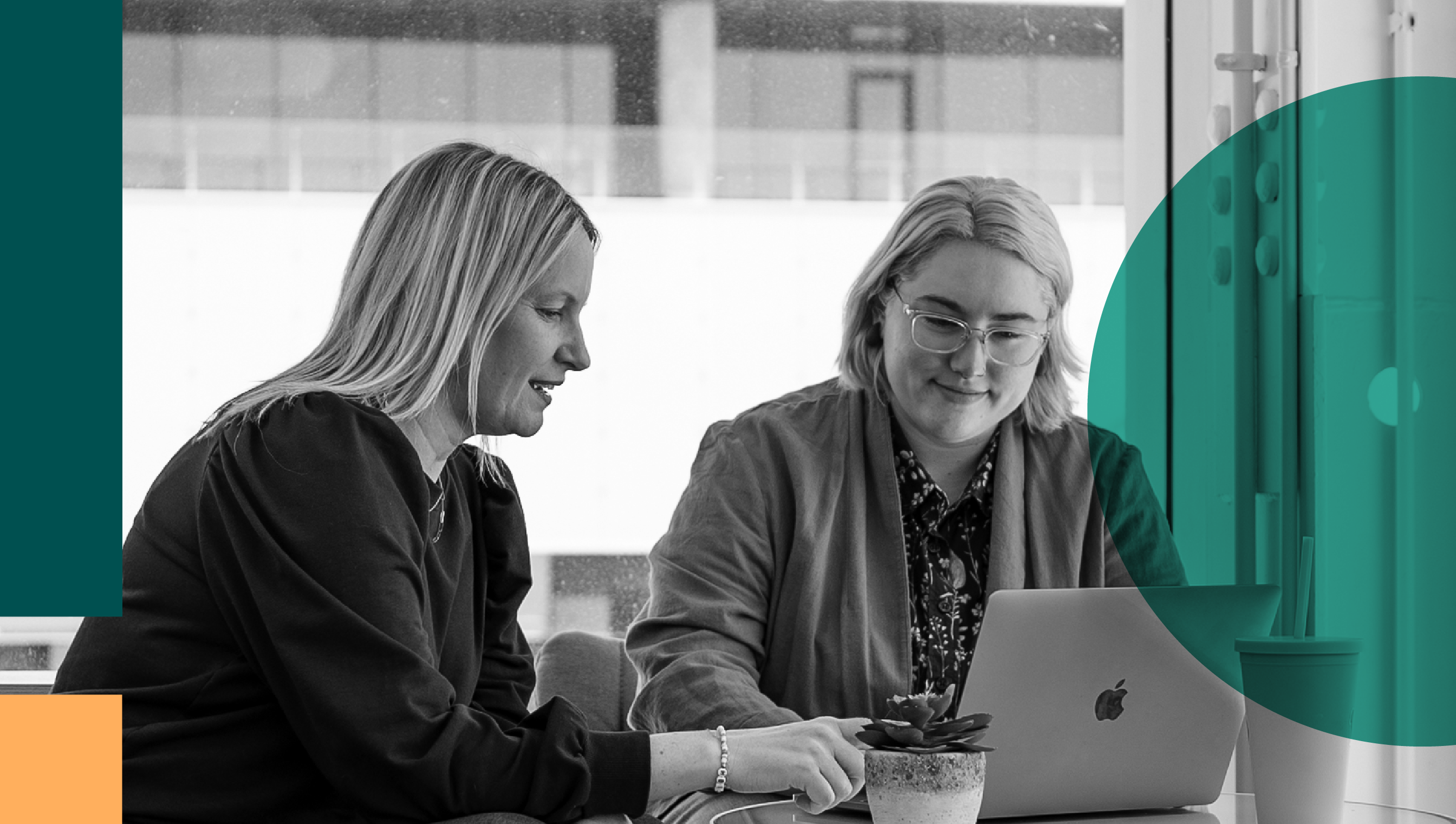 Two women talking in front of a computer and smiling.