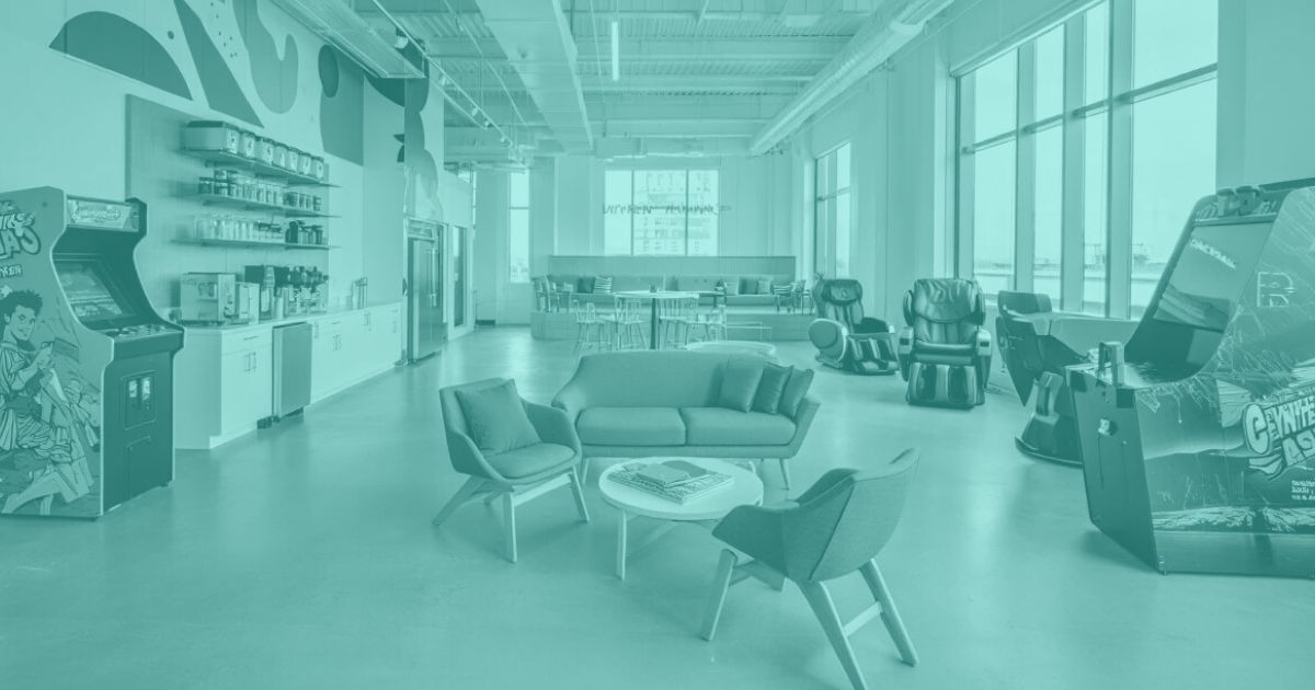 Picture of a break room with tables and games which looks like fun. It's all empty with no employees or people using the room.