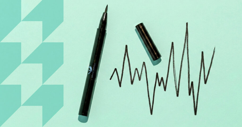 A pen with it's cap off, sits next to a hand-drawn line chart.