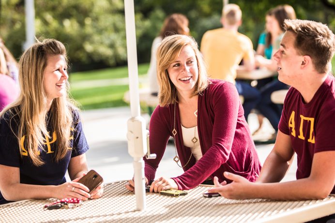Doane University students sitting and talking around an outdoor table
